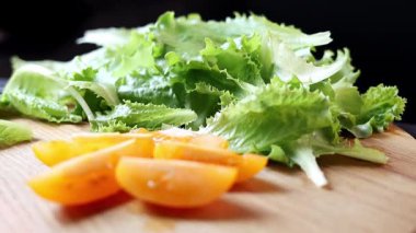 Domateslerin ve marulların yakın plan çekimleri. Siyah arka planda tahta bir tahta üzerinde. Sağlıklı beslenme ve organik tarım ürünleri kavramı. Yavaş çekim.