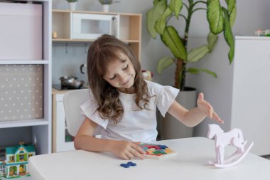 Küçük kız çocuk odasındaki masada masa eğitimi üzerine oyun oynuyordu. Çocuk gelişimi kavramı. Çocuklar için boş zaman kavramı..