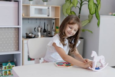 Küçük kız çocuk odasındaki masada masa eğitimi üzerine oyun oynuyordu. Çocuk gelişimi kavramı. Çocuklar için boş zaman kavramı..