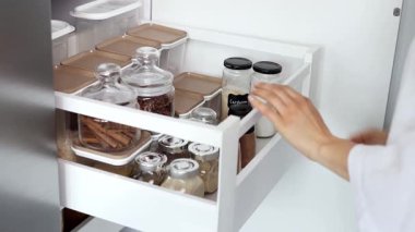 Kadın ellerinin yavaş çekimde baharatlarla bir çekmeceyi kapatması. Mutfakta baharat depoluyor. Ev rutini.