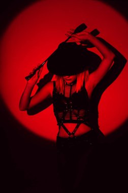 sexy woman in beautiful underwear holds a leather flogger whip in her hands for BDSM sex with submission and domination