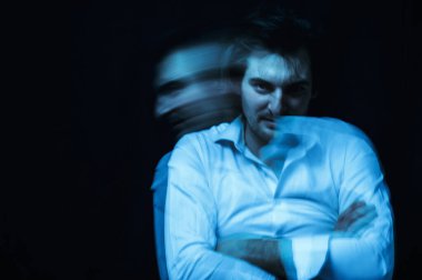 schizophrenic portrait of psychopathic man with mental disorders in white shirt on dark background