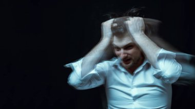 schizophrenic portrait of psychopathic man with mental disorders in white shirt on dark background