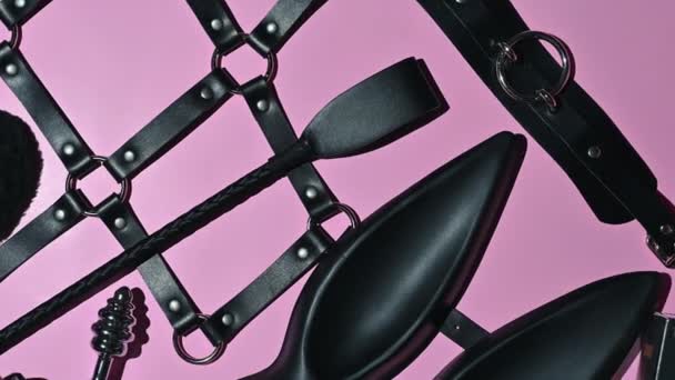 Bdsmセックスのための大人のエロおもちゃのセット提出と支配 革の鞭 ピンクの背景のマスク — ストック動画