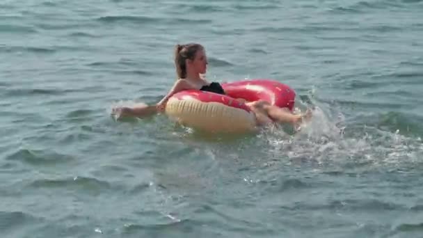 穿着泳衣的小女孩在一个充气的圆环上游泳 夏天是放假的日子 — 图库视频影像