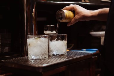 Barmen bardaki buzlu kokteyle limonata döker.