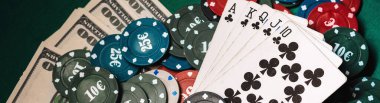 Poker oyununda para ve fiş yığını üzerinde Royal floşu olan kartlar.
