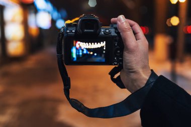 Fotoğrafçıların eli gece modern aynasız kamerayla güzel bir bokeh ile fotoğraf çeker.