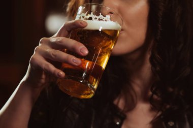 Kadın cinsel olarak köpüklü bira bardağından içer.