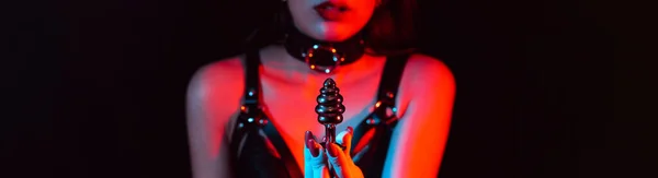 stock image metal butt plug in the hands of a slave girl with a choker and a leather belt. Panoramic wide horizontal photo for banner head cover