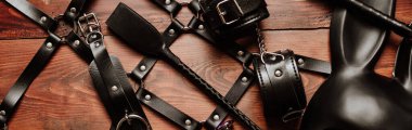 Sert BDSM seksi için bir dizi seks oyuncağı egemenlik ve boyun eğme ile. Deri kırbaç, kelepçe, kemer, şok maskesi ve anal tıpa. Panoramik geniş yatay fotoğraf afiş baş örtüsü için