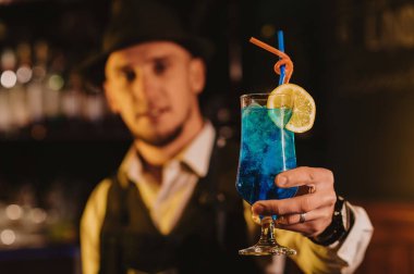 Barmen bardakta bardakta mavi lagün ikram eder. Lokantadaki tezgahta pipetle.