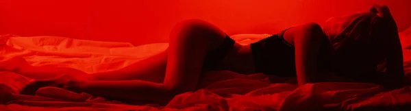 身材纤细的女孩 性感地躺在床上 身上闪烁着红光 横幅头盖全景横向照片 — 图库照片