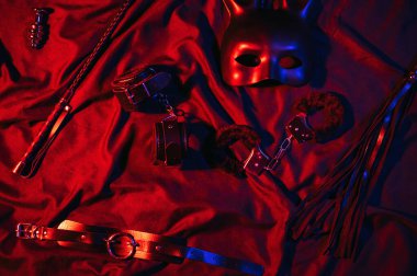 Handcuffs, leather whip flogger, mask and choker for BDSM sex with submission and domination. Concept of erotic adult sex toys