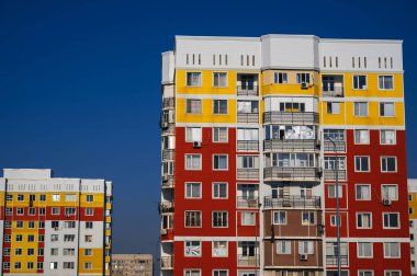 mavi gökyüzü arka planında pencereleri ve balkonları olan yeni evler