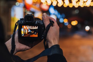 Fotoğrafçıların eli gece modern aynasız kamerayla güzel bir bokeh ile fotoğraf çeker.