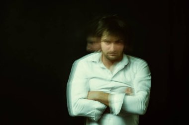 schizophrenic portrait of psychopathic man with mental disorders in white shirt on dark background