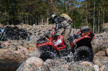 KARELİYA, RUSSIA REÜKLİK - CIRCA HAZİRAN 2022: Karelia 'da Ladoga Kupası 2022 off-road turnuvası. ATV yarışçısı taşlara biner ve doğada bir yarışta ırmağın üstesinden gelir.