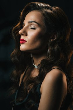 1950 'lerin klasik eski tarz Hollywood filmlerinde güzel saç stili ve makyajlı şık bir kadın. Koyu arkaplanda takıları olan klasik görünümlü bir kızın portresi.