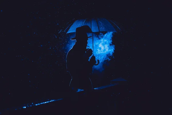 Mężczyzna Detektyw Kapeluszu Płaszczu Przeciwdeszczowym Pod Parasolem Pali Nocy Deszczowym — Zdjęcie stockowe