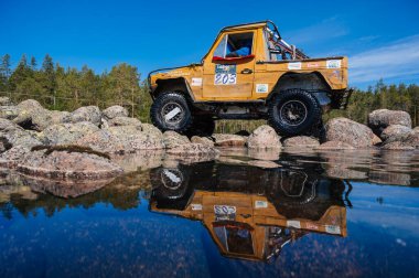 KARELİYA, RUSSIA REUKLİK - CIRCA HAZİRAN, 2022: Ladoga Gölü çevresindeki off-road turnuvası Ladoga Kupası 2022. 4x4 Mercedes göl kıyısındaki kayalıklarda geziniyor.