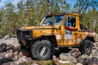 KARELİYA, RUSSIA REUKLİK - CIRCA HAZİRAN, 2022: Ladoga Gölü çevresindeki off-road turnuvası Ladoga Kupası 2022. 4x4 Mercedes yazın doğada bir off-road yarışında kayaların üzerinden geçiyor.