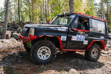 KARELİYA, RUSSIA REUKLİK - CIRCA HAZİRAN, 2022: Ladoga Gölü çevresindeki off-road turnuvası Ladoga Kupası 2022. 4x4 Jeep arazi aracı ormanın ortasında kayaların üzerinden geçiyor.