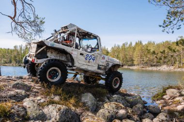 KARELİYA, RUSSIA REUKLİK - CIRCA HAZİRAN, 2022: Ladoga Gölü çevresindeki off-road turnuvası Ladoga Kupası 2022. 4x4 Mercedes cipi yarışta kayalıklarda geziyor.