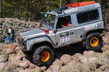 KARELİYA, RUSSIA REUKLİK - CIRCA HAZİRAN, 2022: Ladoga Gölü çevresindeki off-road turnuvası Ladoga Kupası 2022. 4x4 SUV off-road yarışında kayaların üzerinden geçiyor.