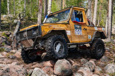 KARELİYA, RUSSIA REUKLİK - CIRCA HAZİRAN, 2022: Ladoga Gölü çevresindeki off-road turnuvası Ladoga Kupası 2022. 4x4 Mercedes yazın doğada bir off-road yarışında kayaların üzerinden geçiyor.