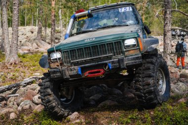 KARELİYA, RUSSIA REUKLİK - CIRCA HAZİRAN, 2022: Ladoga Gölü çevresindeki off-road turnuvası Ladoga Kupası 2022. 4x4 SUV yazın doğada bir off-road yarışında kayaların üzerinden geçer.