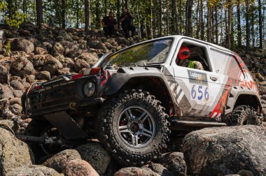 KARELİYA, RUSSIA REUKLİK - CIRCA HAZİRAN, 2022: Ladoga Gölü çevresindeki off-road turnuvası Ladoga Kupası 2022. Niva 4x4 off-road arabaları ormanın ortasında kayalıklarda yarışır.