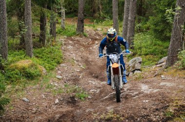 KARELİYA, RUSSIA REÜKLİK - CIRCA HAZİRAN 2022: Karelia 'da Ladoga Kupası 2022 off-road turnuvası. Enduro spor motosikletine binen motosikletli bir motosikletli ormandaki kayaların üzerinde motokros yarışı yapıyor.