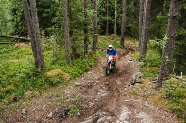 KARELİYA, RUSSIA REÜKLİK - CIRCA HAZİRAN 2022: Karelia 'da Ladoga Kupası 2022 off-road turnuvası. Enduro spor motosikletine binen motosikletli bir motosikletli ormandaki kayaların üzerinde motokros yarışı yapıyor.