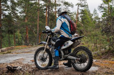 KARELİYA, RUSSIA REÜKLİK - CIRCA HAZİRAN 2022: Karelia 'da Ladoga Kupası 2022 off-road turnuvası. Spora dayanıklı motosiklet kullanan bir motosikletçi zorlu bir orman arazisinde motosiklet yarışı yapıyor.