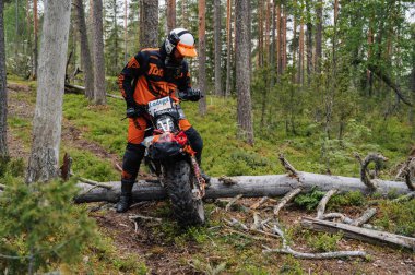 KARELİYA, RUSSIA REÜKLİK - CIRCA HAZİRAN 2022: Karelia 'da Ladoga Kupası 2022 off-road turnuvası. Motosikletli bir kask spor motosikletli bir kask ormanda kayalık bir yolda motosiklet sürüyor.