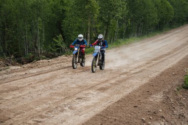 KARELİYA, RUSSIA REÜKLİK - CIRCA HAZİRAN 2022: Karelia 'da Ladoga Kupası 2022 off-road turnuvası. Bir motosiklet yarışçısı spor bir motosiklet üzerinde tozlu bir yolda motosiklet yarışına katılır.