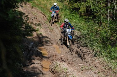 KARELİYA, RUSSIA REÜKLİK - CIRCA HAZİRAN 2022: Karelia 'da Ladoga Kupası 2022 off-road turnuvası. Dayanıklı spor motosikletli bir motosiklet yarışçısı orman yolunda çamurda kayıyor.