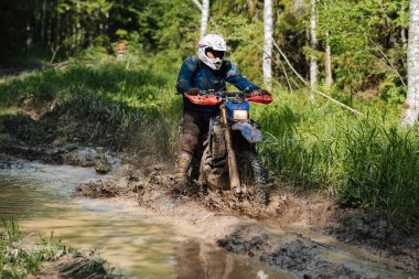 KARELİYA, RUSSIA REÜKLİK - CIRCA HAZİRAN 2022: Karelia 'da Ladoga Kupası 2022 off-road turnuvası. Motosiklet yarışçısı spor motosikletinde çamurlu orman yollarında geziyor.