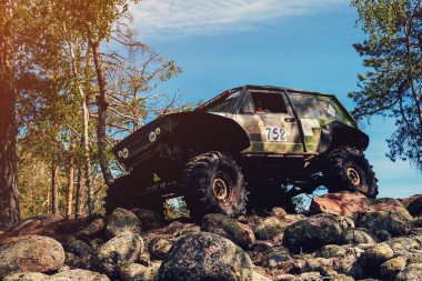 4x4 SUV yazın güneşli bir günde off-road yarışında kayalar.