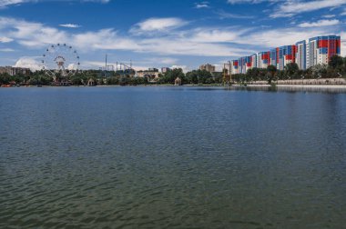 SHYMKENT, KAZAKHSTAN - 07 Temmuz 2023: Yazın Şymkent 'teki gölden Altyn Göz Parkı ve dönme dolap manzarası