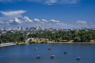 Yazın Şymkent 'teki Altyn Göz Parkı' nın dönme dolabının ve gölün üst manzarası.