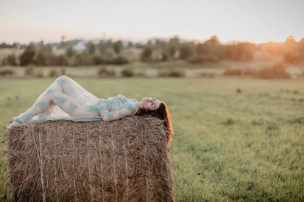 性感的裸体女孩赤身裸体躺在田野里的草堆上 添加了一个小薄膜颗粒的效果 图库图片