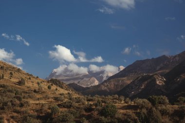 Dağ zirveleri olan manzara yazın gün batımında bulutlarla gökyüzü.