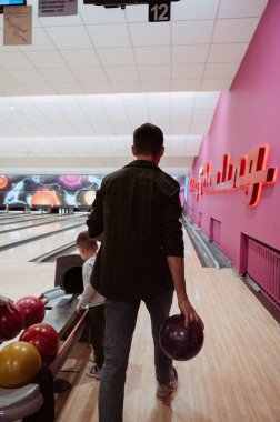 Baba ve oğul kulüpte bowling oynuyorlar.