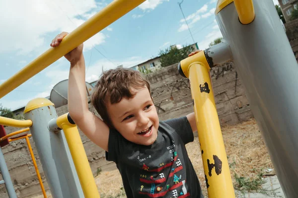 stock image preschooler boy plays on simulators on the playground in the summer