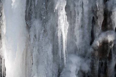 Donmuş buz saçakları ve kışın taş bir duvarın üzerindeki krema.