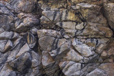 Gri kayalık bir dağın yüzey dokusunda çatlaklar var.