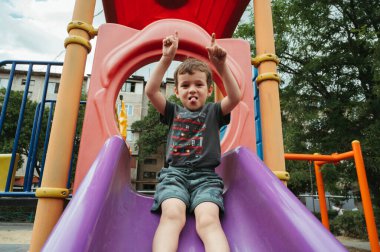 Çocuk yazın oyun parkında slaytla oynar.