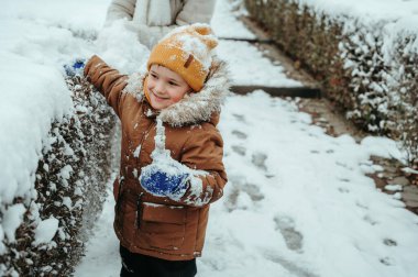 Mutlu küçük çocuk kışın parkta oynuyor.